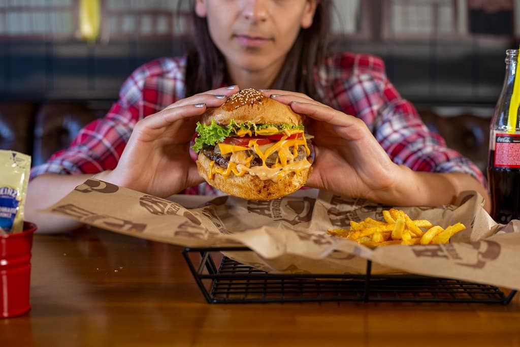 man in red and white plaid dress shirt holding burger